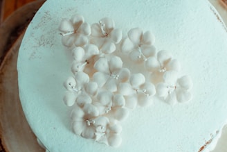 A close-up of a delicately frosted wedding cake adorned with fresh white flowers and subtle greenery.