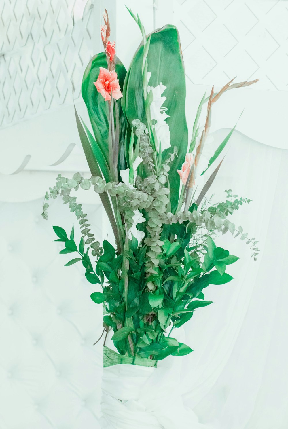 a white vase filled with lots of green plants