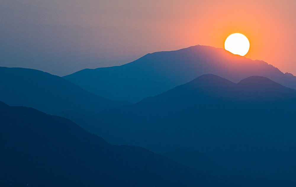 the sun is setting over a mountain range