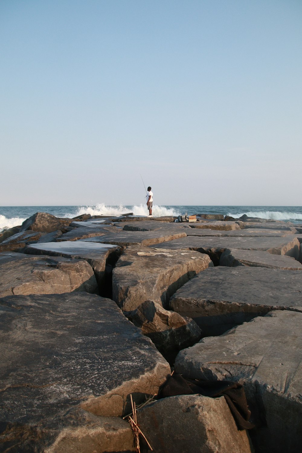 um homem em pé no topo de uma praia coberta de rocha