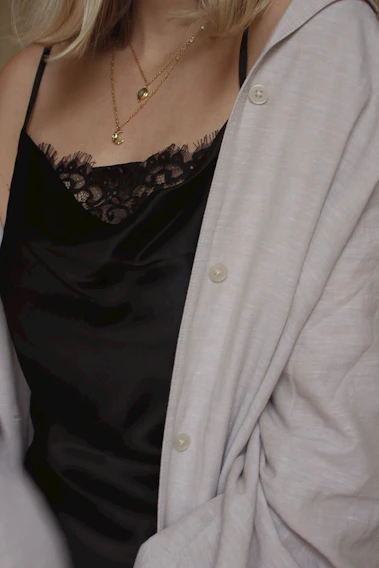 A close-up shot of a chic outfit featuring layered gold necklaces and a soft cashmere sweater in muted tones.