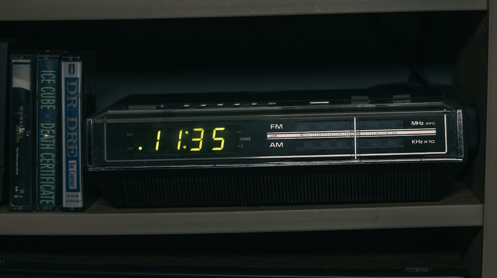 an alarm clock sitting on top of a book shelf