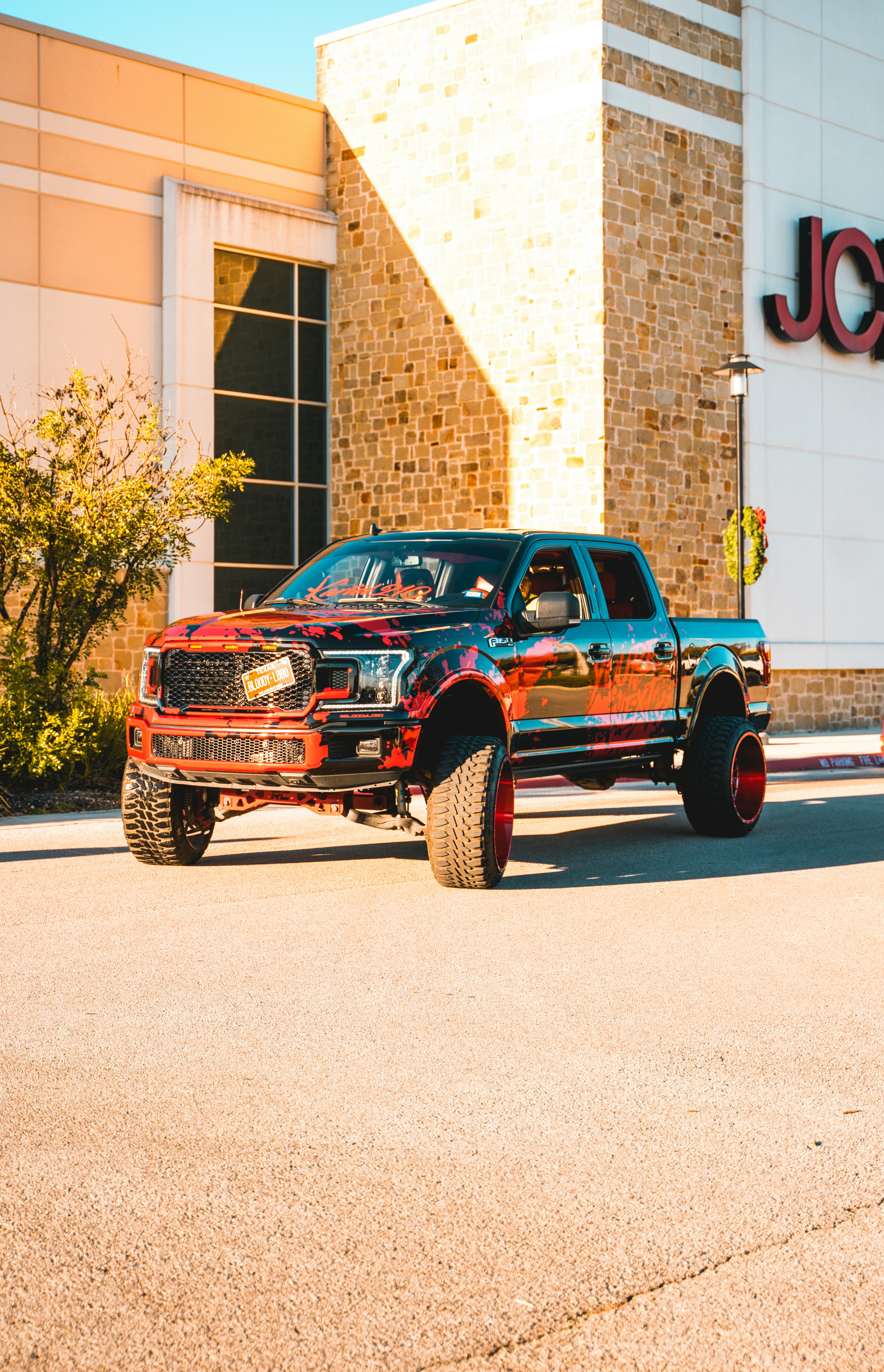 a red and black truck parked in front of a jcc store
