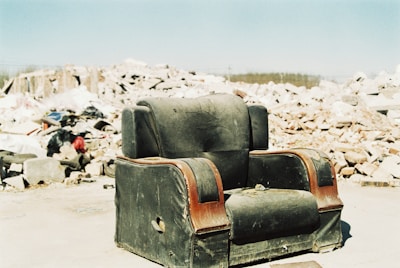 an old chair sitting in front of a pile of rubble
