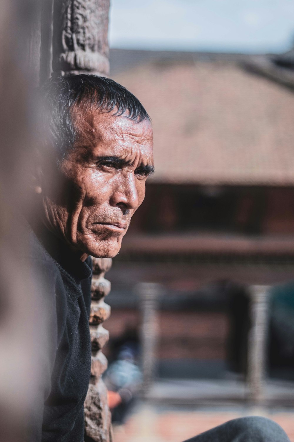 a man sitting on the side of a wooden pole