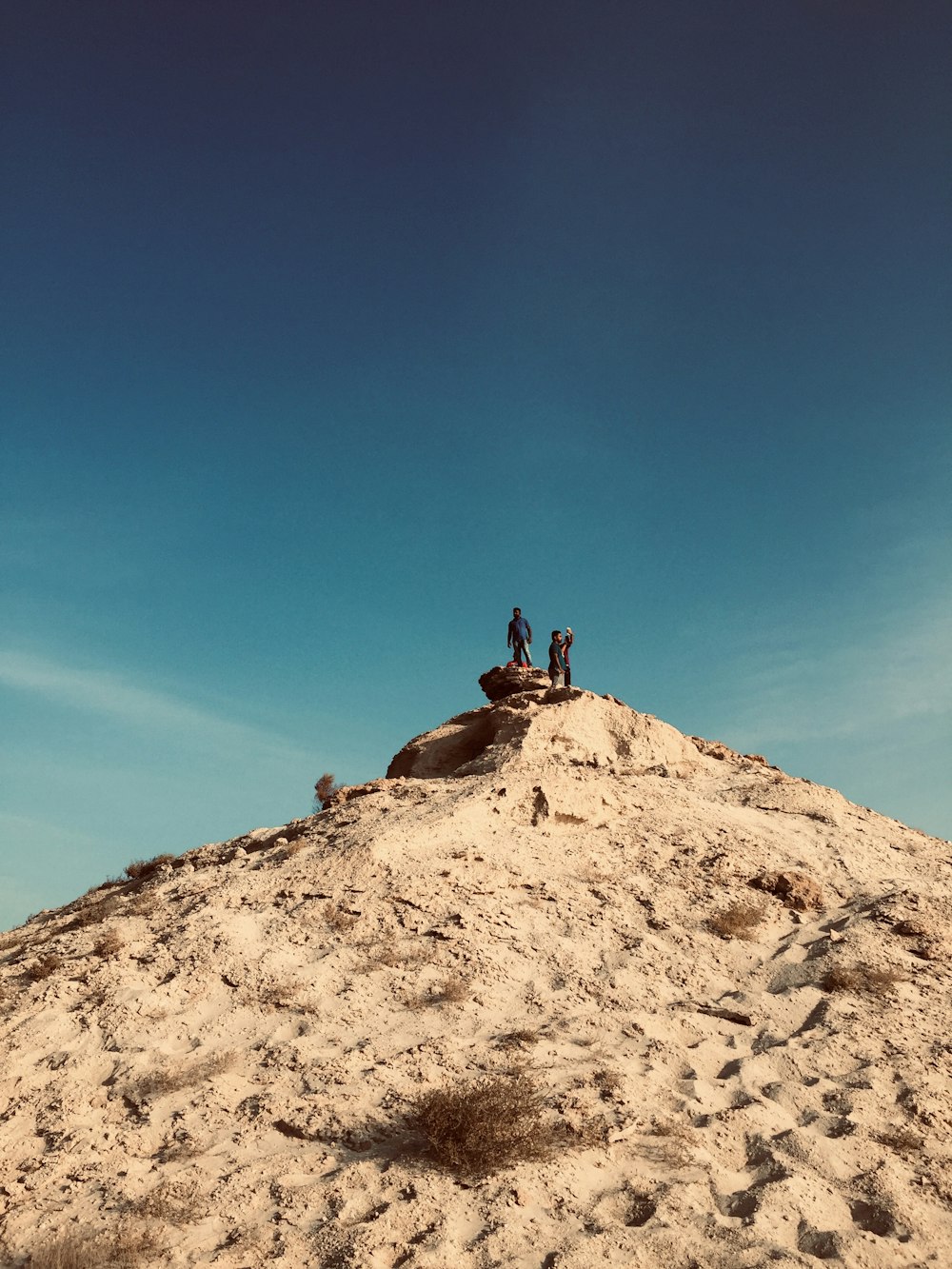 a group of people standing on top of a sandy hill