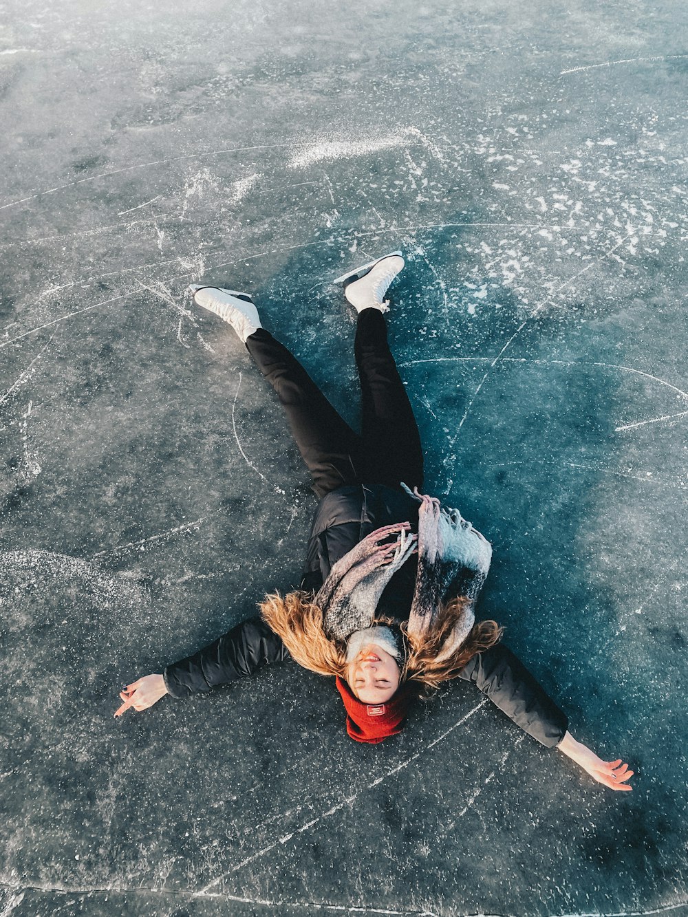 a woman laying on the ice on a frozen lake