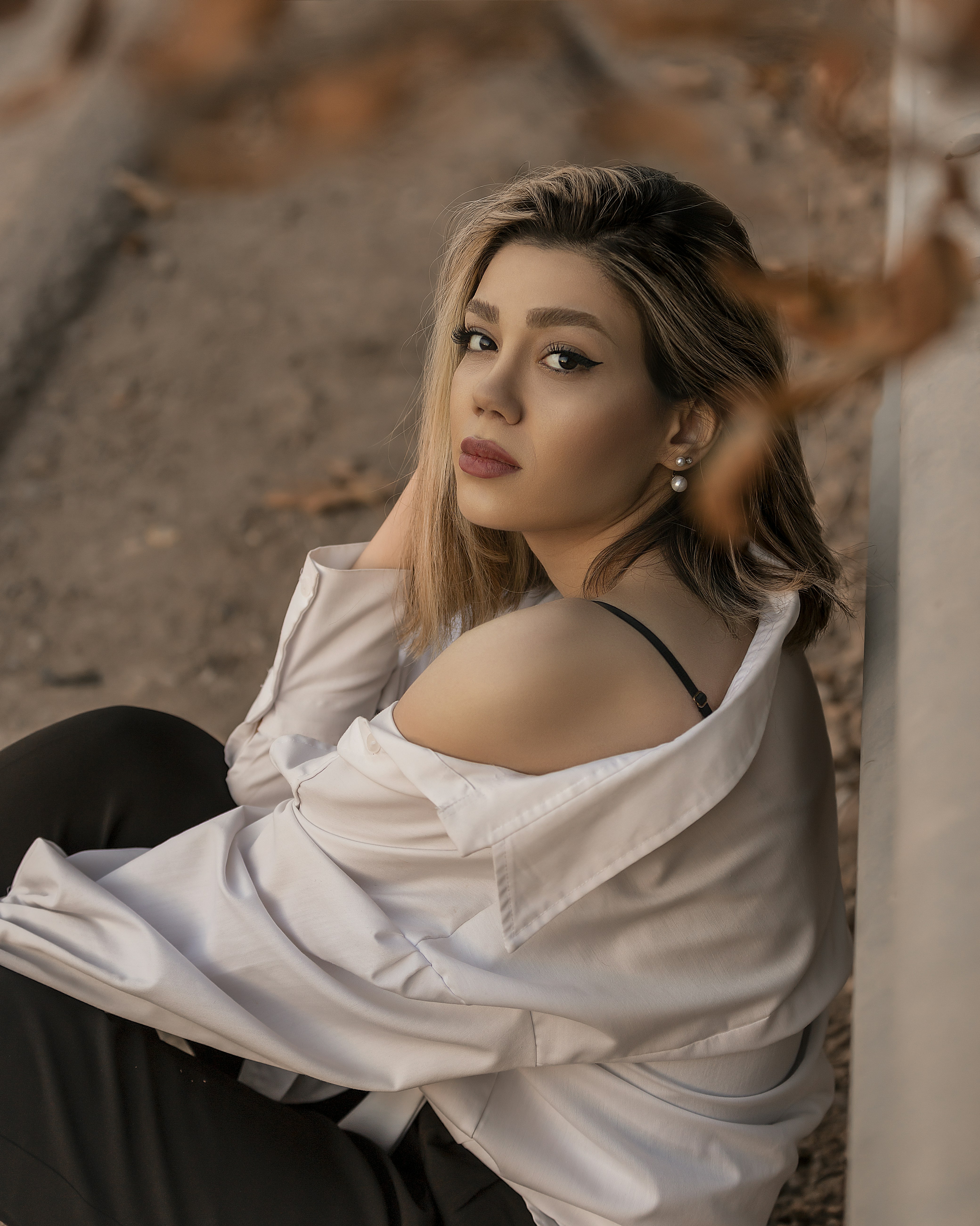 a woman sitting on the ground wearing a white shirt and black pants