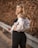 a woman in a white top and black pants
