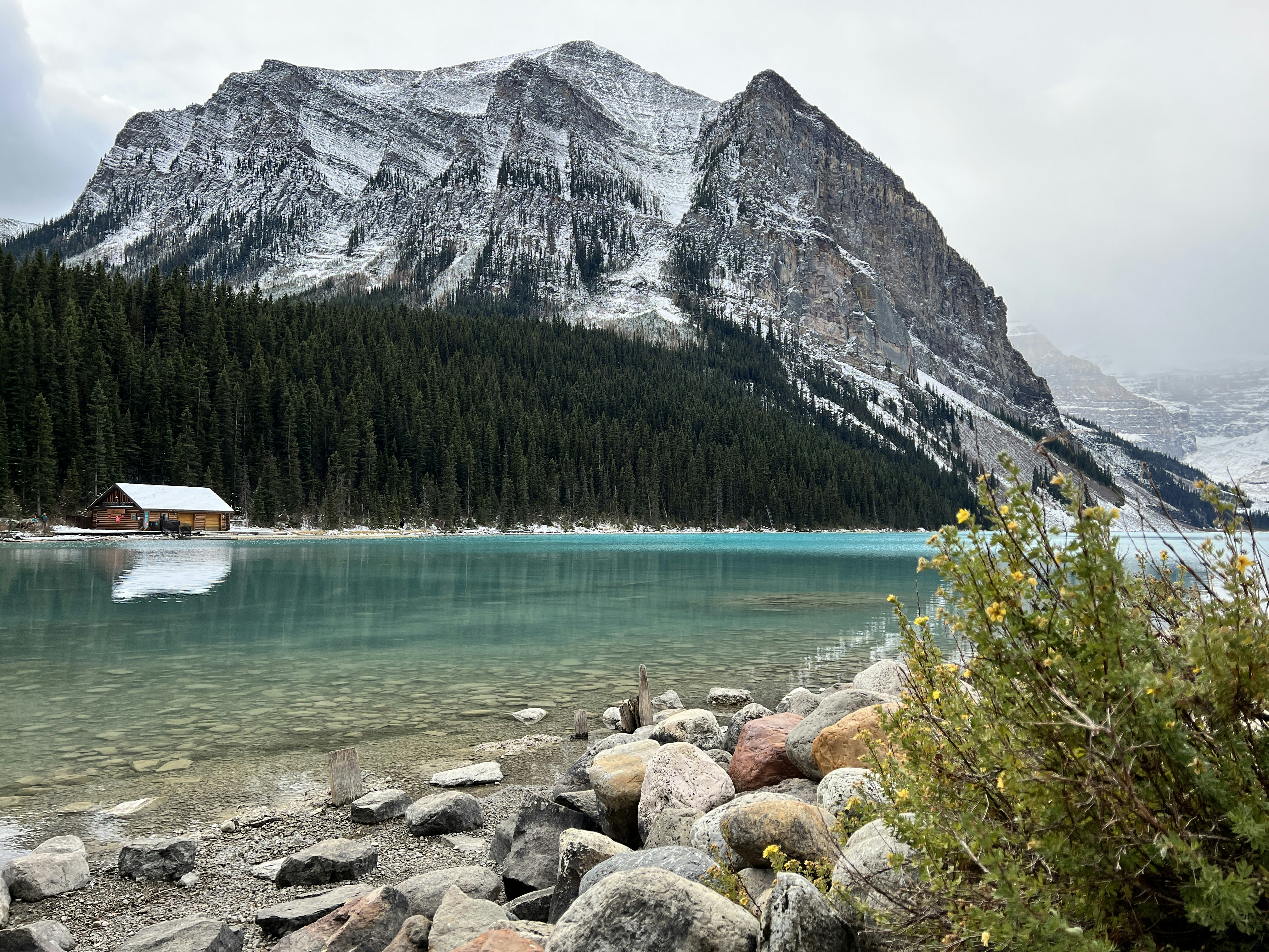 a view of a mountain lake with a cabin in the background