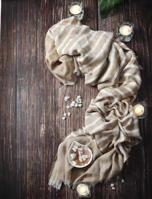 Soft beige fabric draped gently with scattered dried botanicals and isara packaging.