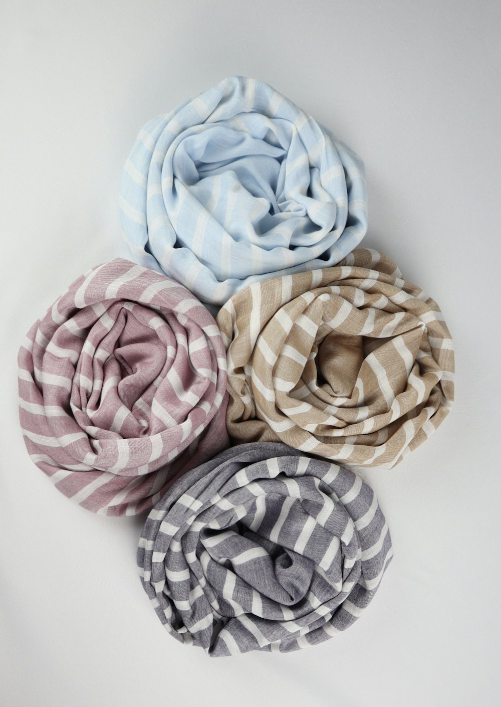four scarves of different colors on a white surface