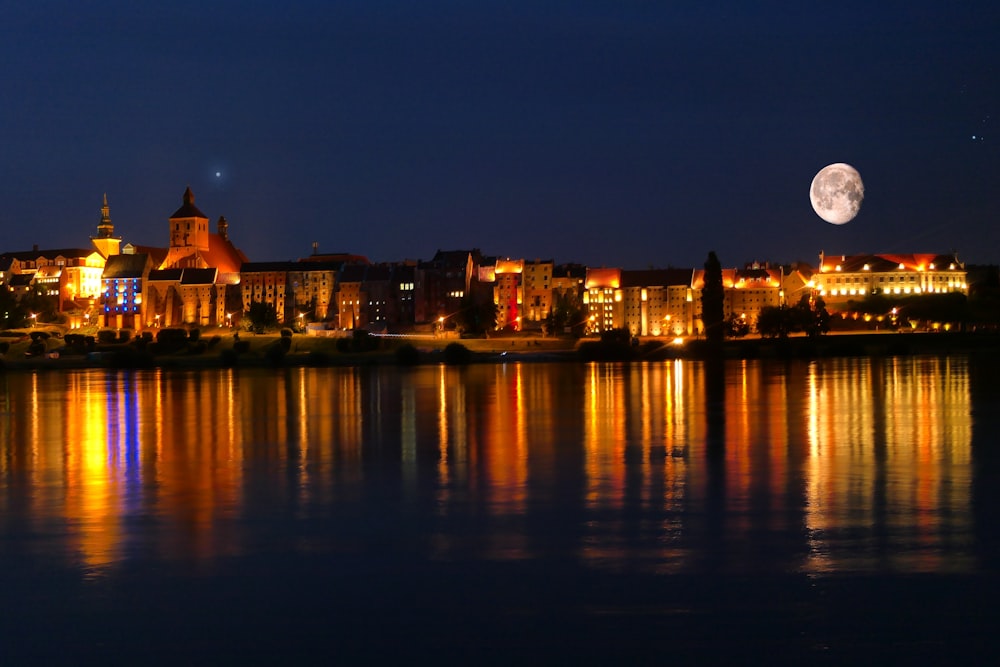 uma lua cheia é vista sobre uma cidade à noite