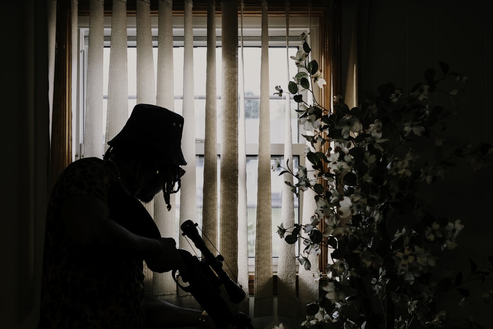 a person with a guitar in front of a window