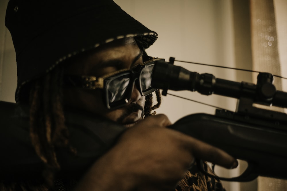 a man holding a rifle and wearing sunglasses