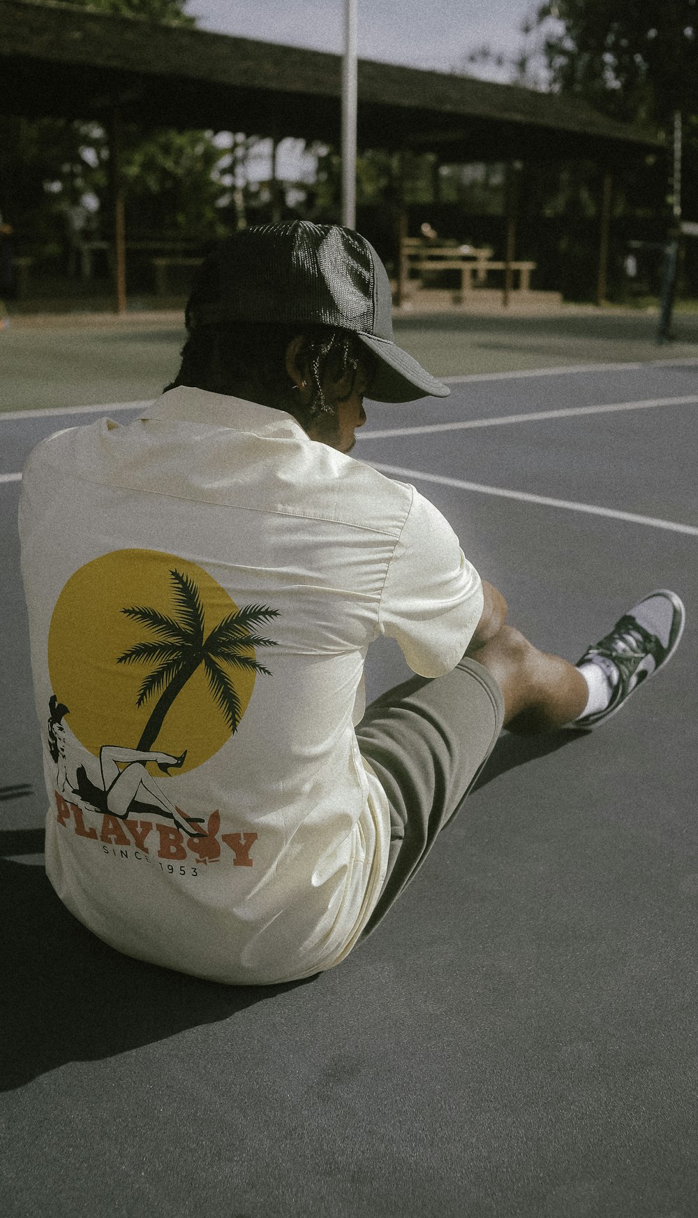 a man sitting on a tennis court wearing a hat