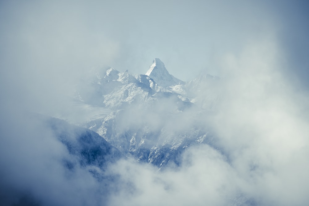 a view of a snow covered mountain in the clouds