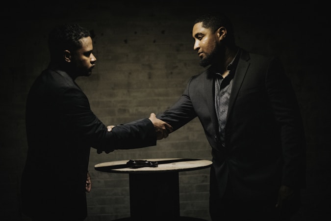 Two people negotiating a music licensing agreement at a table with documents and a laptop