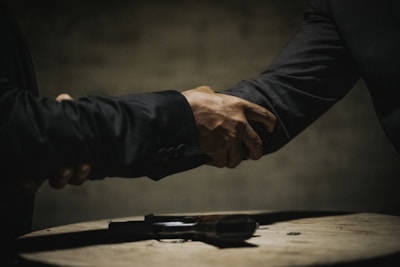 two people shaking hands over a wooden table