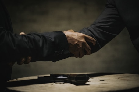 two people shaking hands over a wooden table