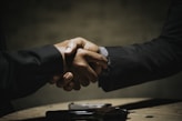 two people shaking hands over a wooden table