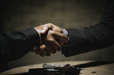 two people shaking hands over a wooden table