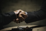 two people shaking hands over a wooden table