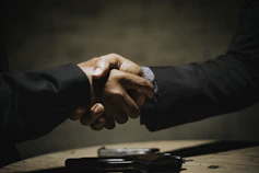 two people shaking hands over a wooden table