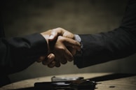 two people shaking hands over a wooden table