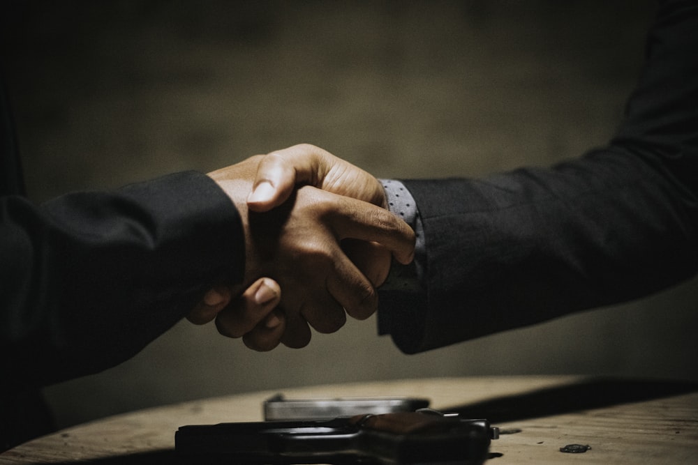 duas pessoas apertando as mãos sobre uma mesa de madeira