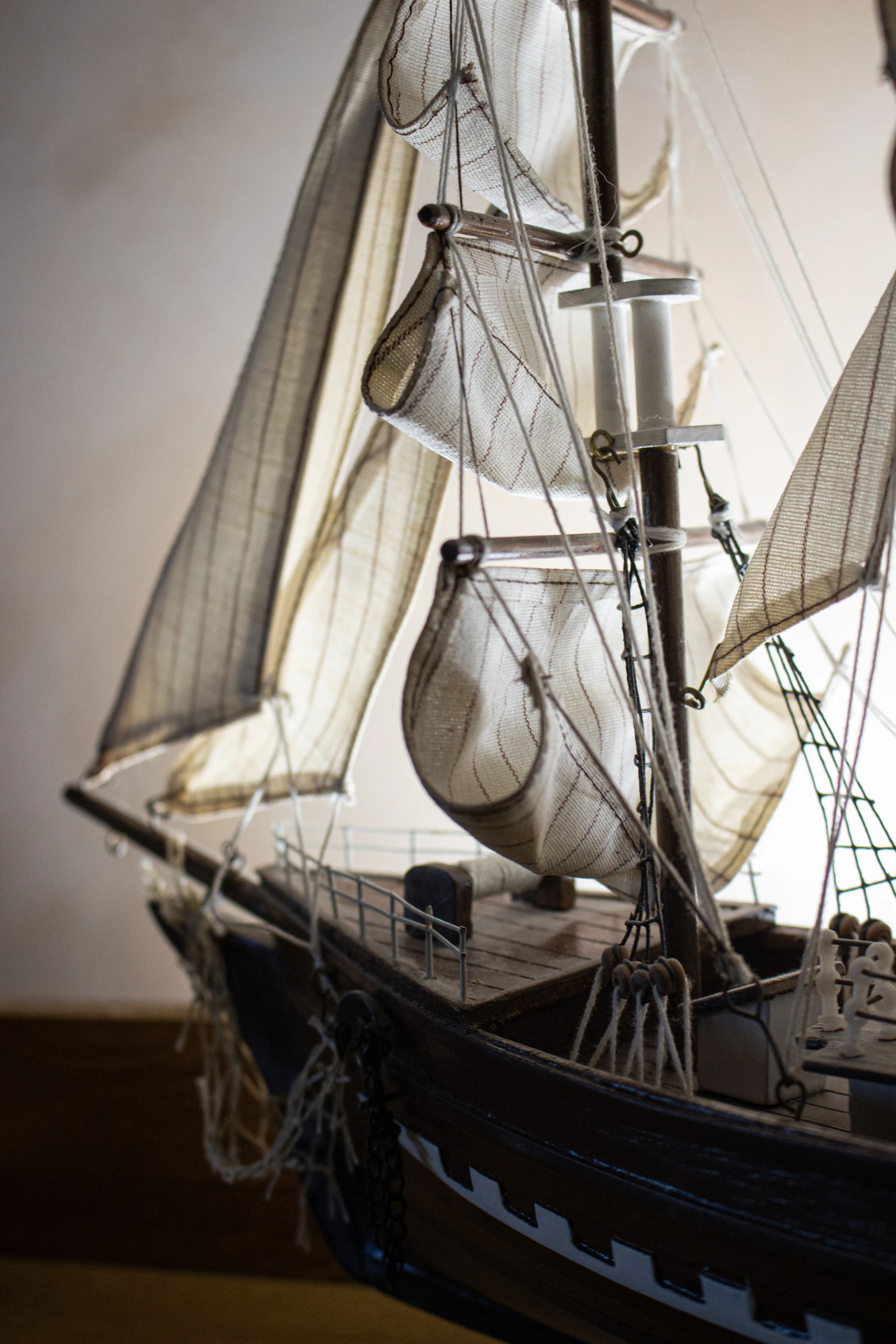 Close-up of the cloth sails and rigging on a dark-hulled model sailing ship
