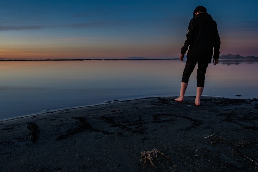 a person standing on a beach at sunset