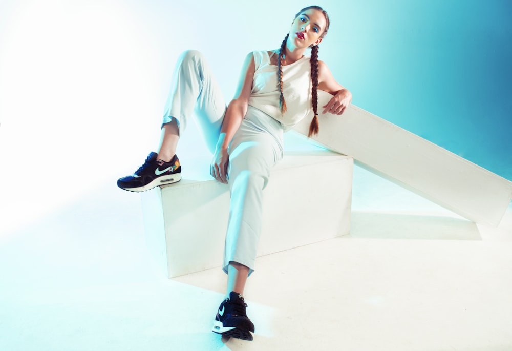 a woman sitting on top of a white block