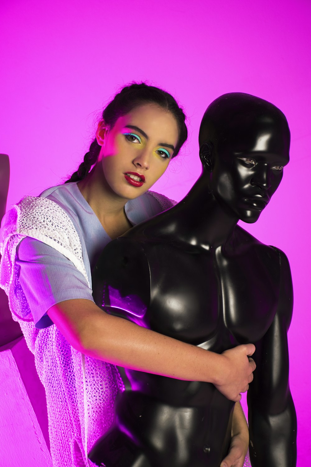 a woman standing next to a black mannequin