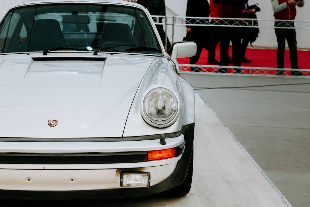 Une Porsche blanche garée devant une foule de gens