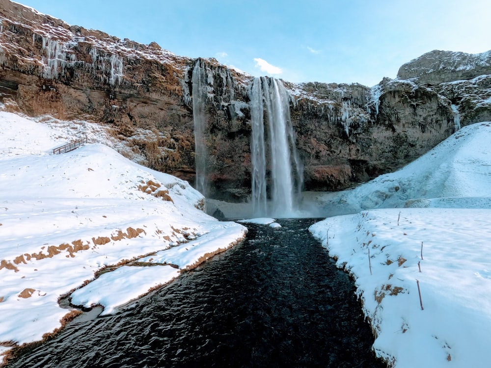 uma cachoeira congelada com neve no chão