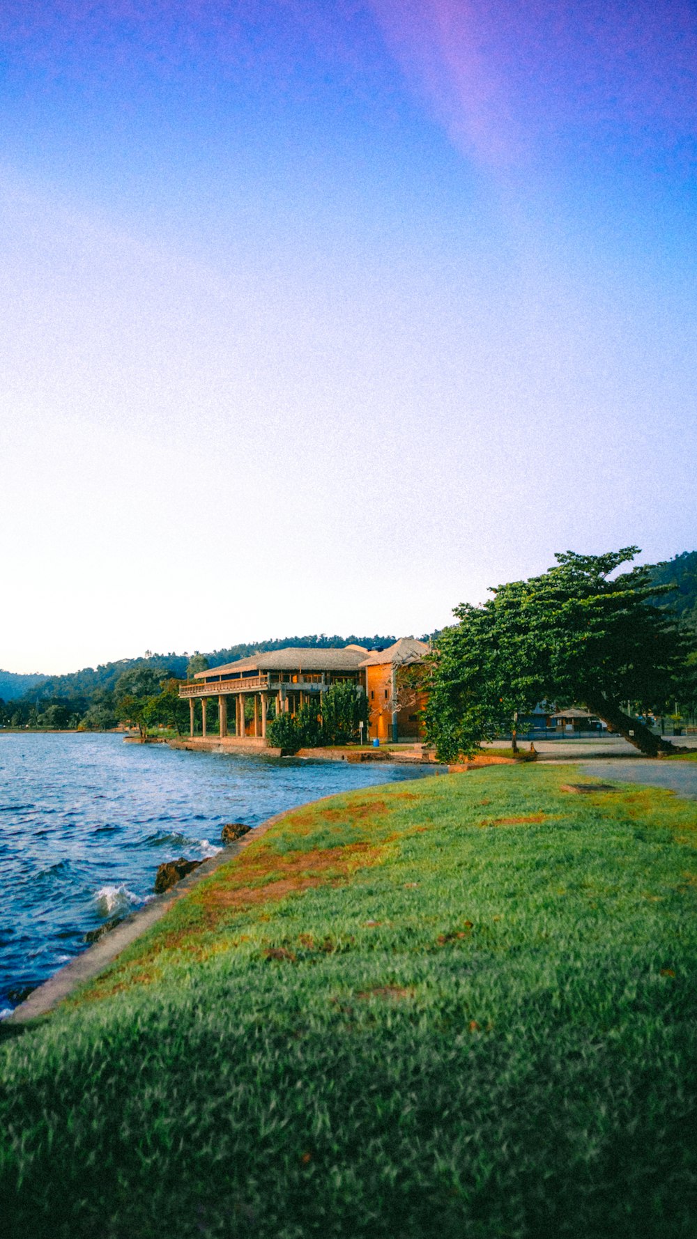 a large body of water sitting next to a lush green field