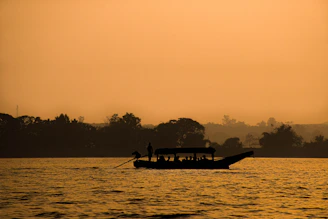 Guests enjoying a serene sunset cruise with warm golden light reflecting off the calm lake.