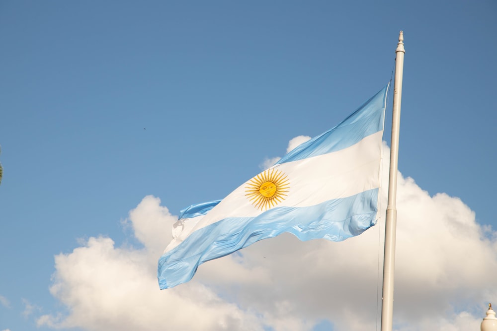 a flag flying in the wind with a clock tower in the background