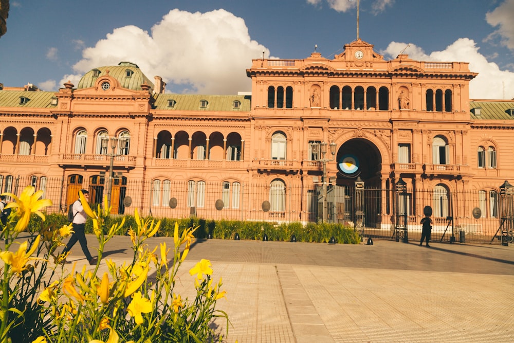 a large building with yellow flowers in front of it