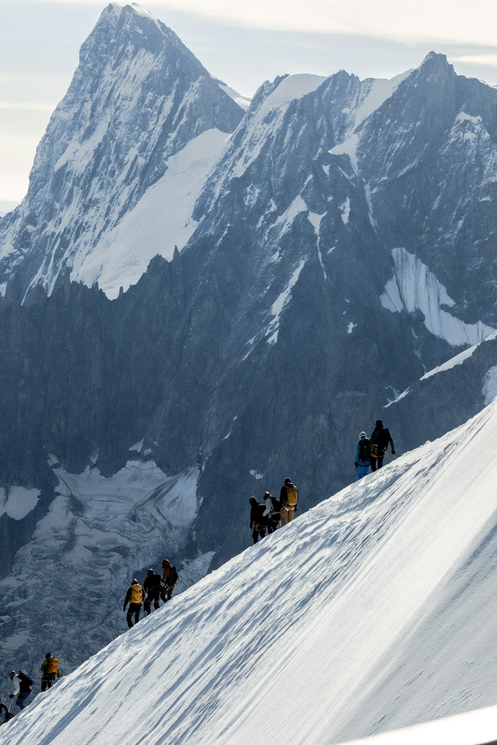 a group of people climbing up the side of a snow covered mountain