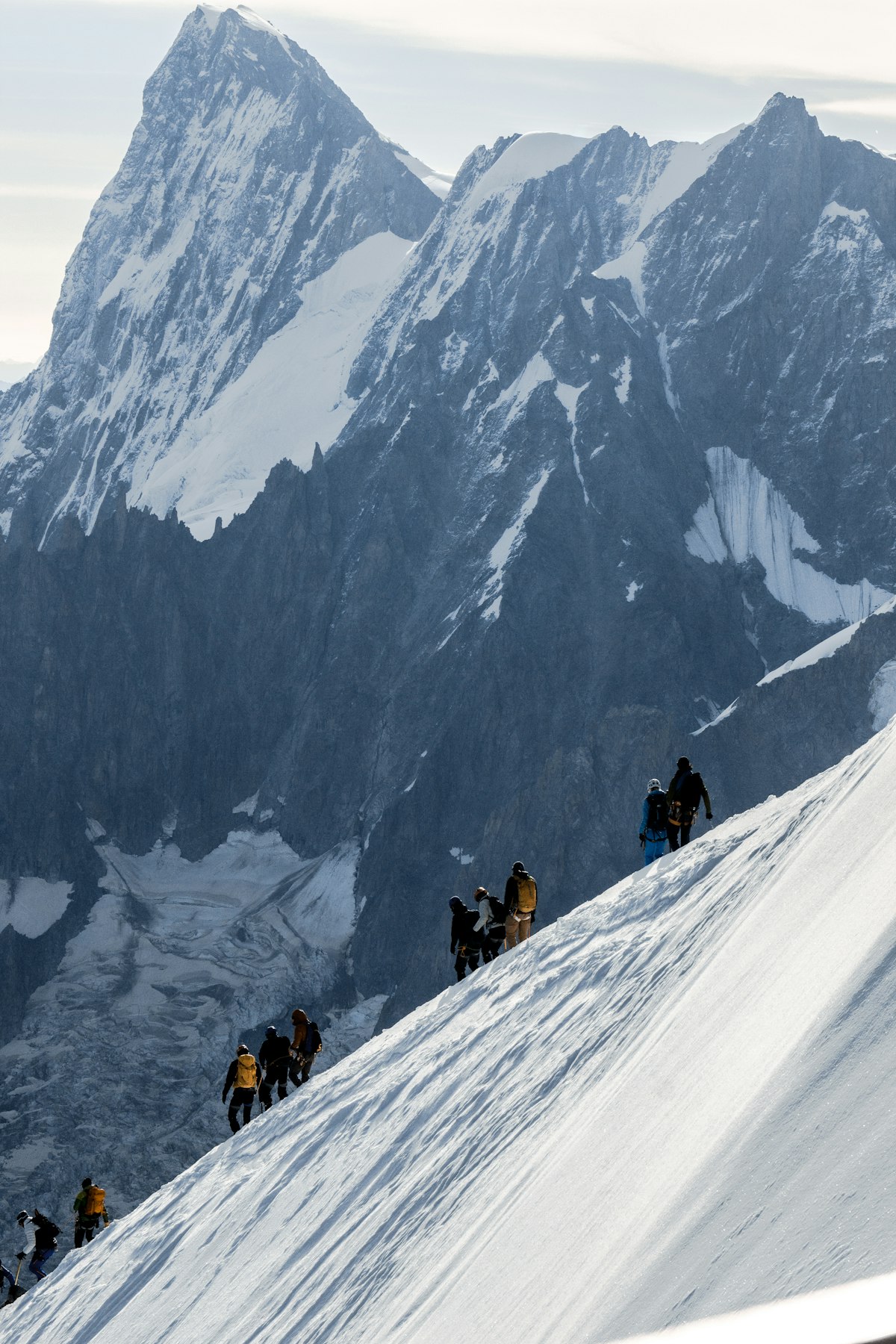 A roped team of mountaineers ascending a snow-covered peak together, servant-leadership register