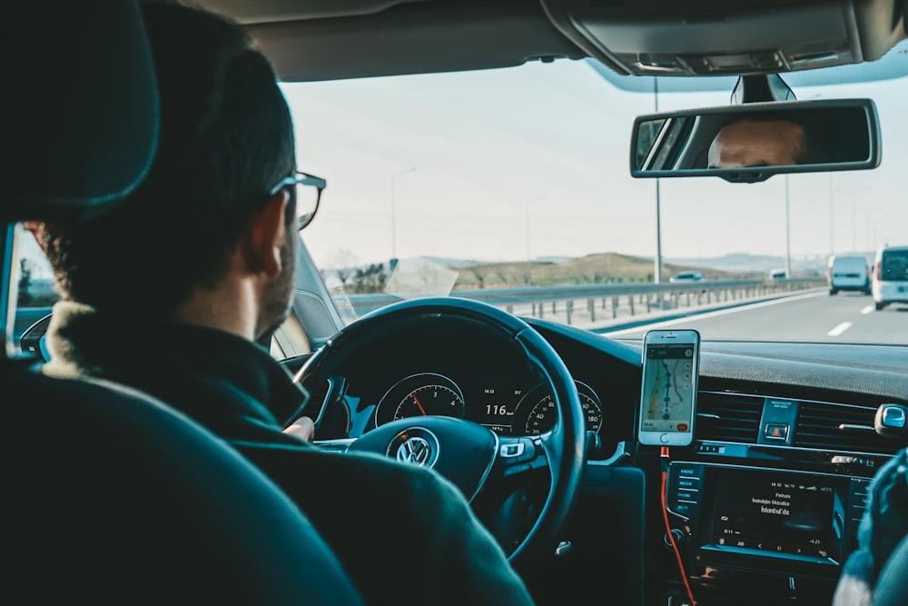 a man driving a car with a cell phone in his hand