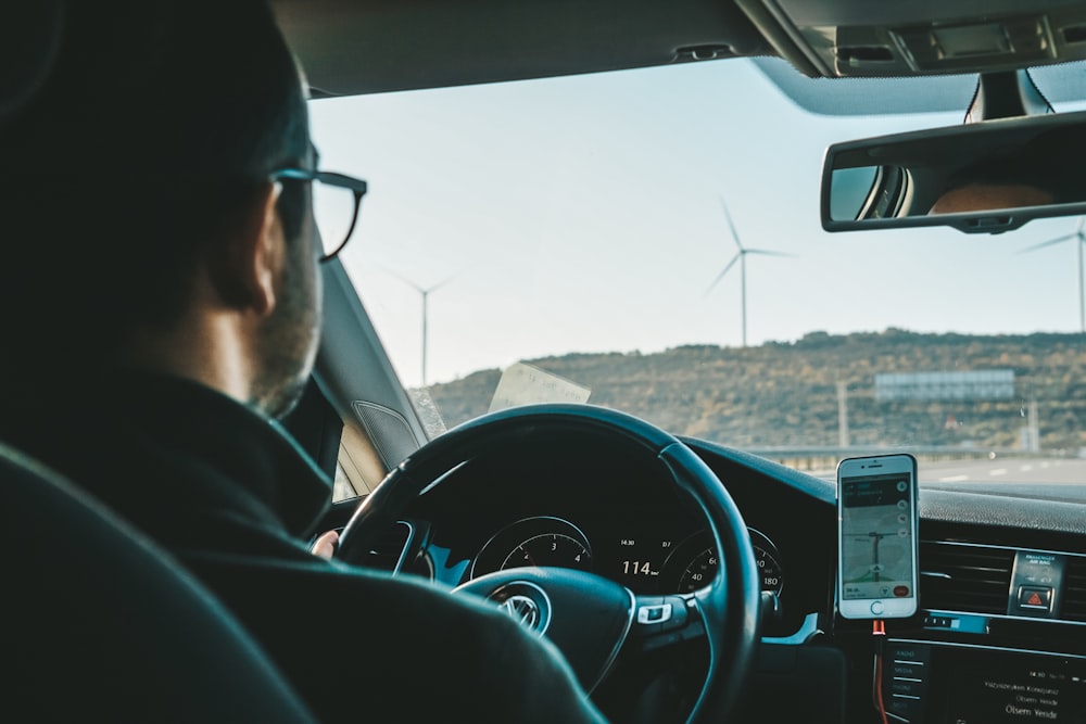 a man driving a car with a cell phone in his hand