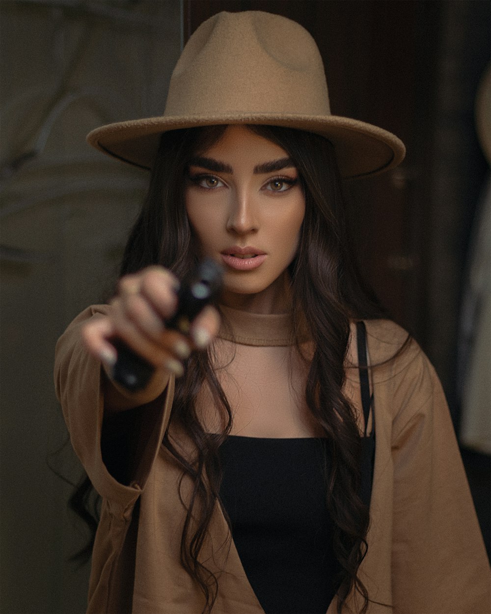 a woman in a brown hat holding a gun