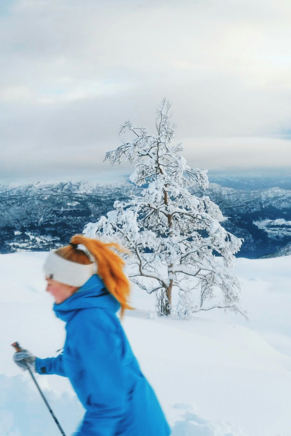 a woman in a blue jacket skiing on a snowy hill