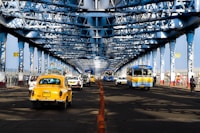 a yellow taxi cab driving down a street under a bridge