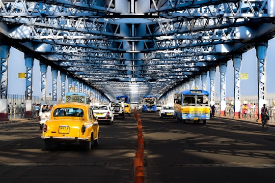 a yellow taxi cab driving down a street under a bridge