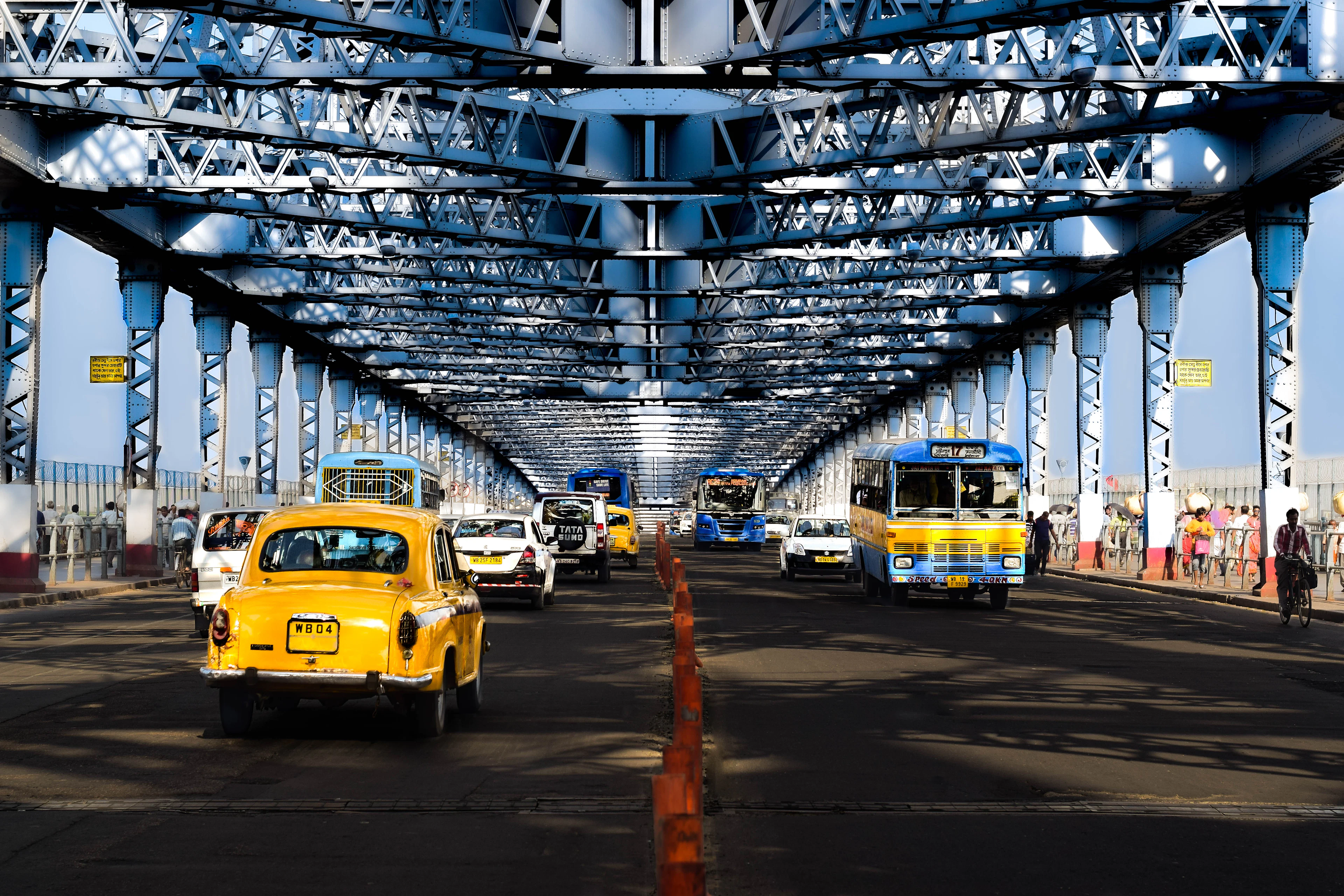 A yellow taxi beneath a bridge in Kolkata