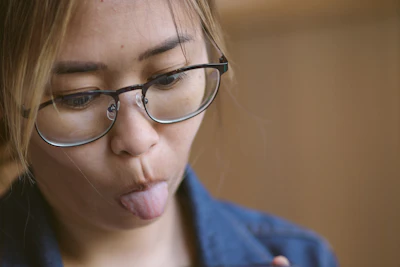 a woman sticking her tongue out with glasses on